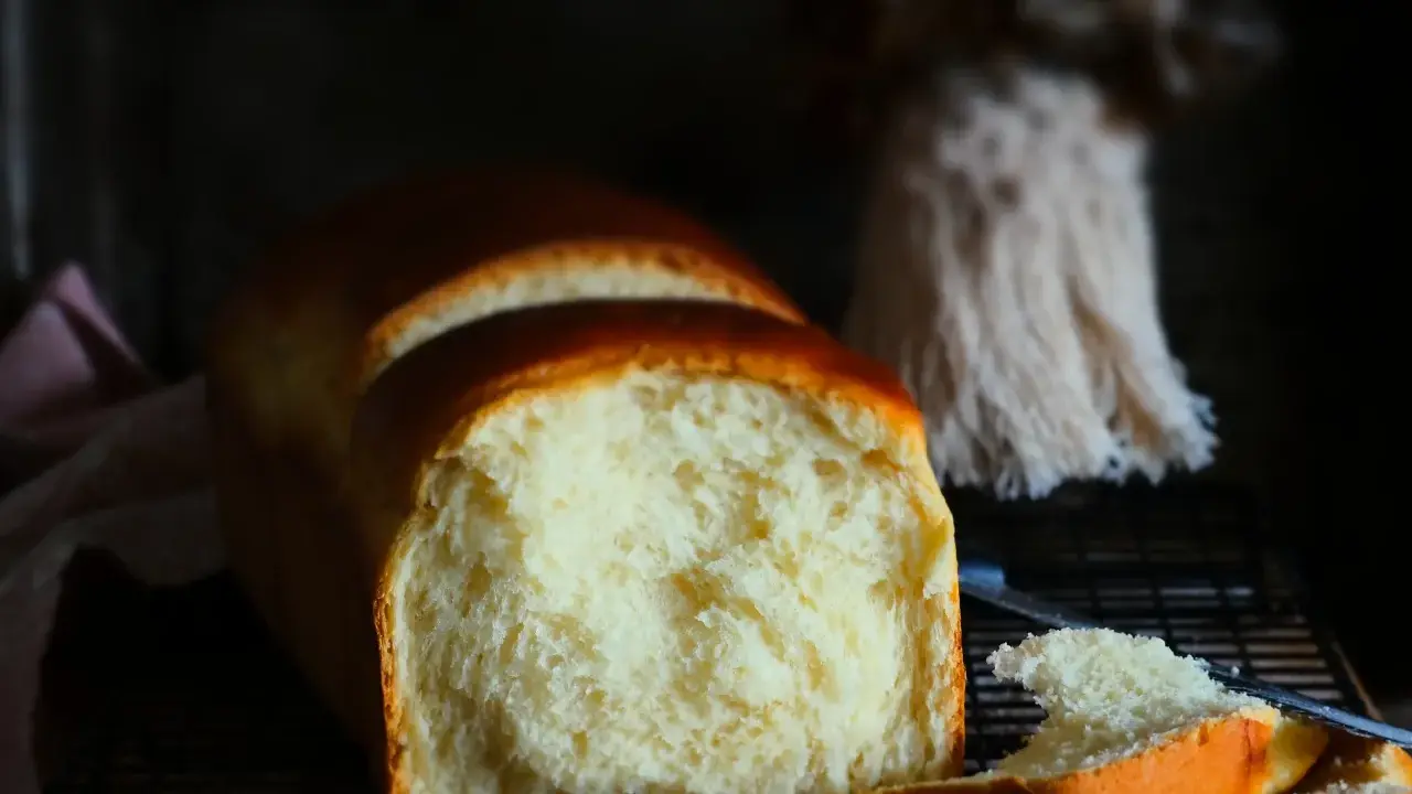 Ein frisch gebackenes Brioche-Brot, das auf einem Rost abkühlt. Die goldbraune Kruste und die weiche, helle Krume lassen das brioche rezept gelingen.