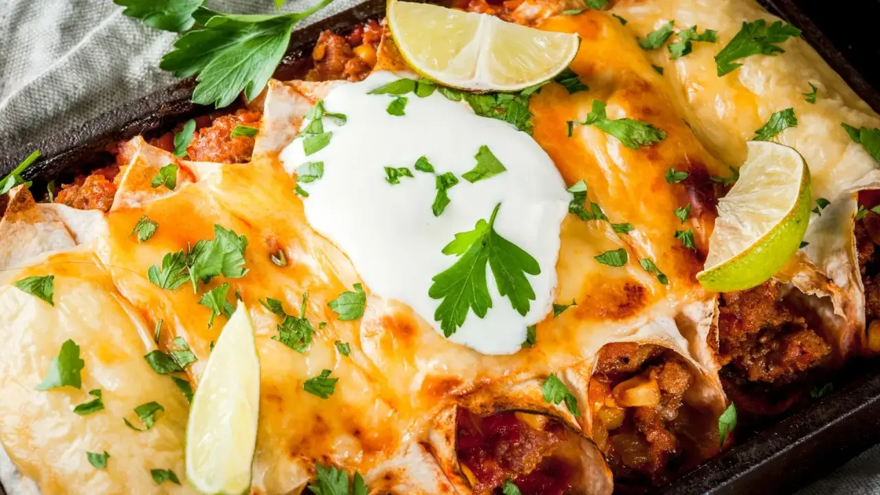 Herzhafte Enchiladas mit geschmolzenem Käse, saurer Sahne und Limettenspalten. Ein köstliches Enchiladas Rezept, das man probieren muss!
