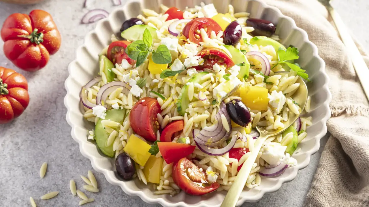 Ein bunter, schneller Kritharaki-Salat mit Tomaten, Gurken, Paprika, roten Zwiebeln, Oliven und Feta.