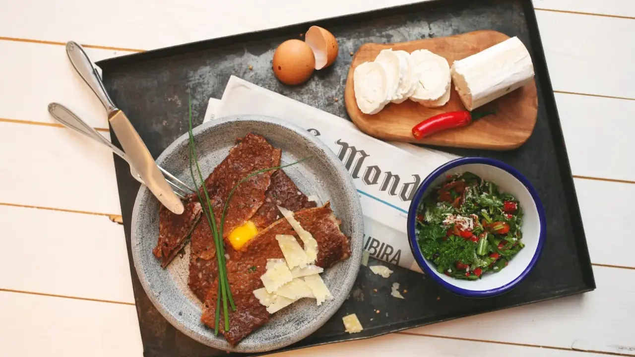 Herzhafte Galette Bretonne mit Ei, Käse und Salat, dazu Ziegenkäse und Chili.