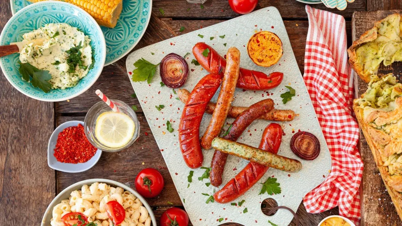 Würstchen, Maiskolben, Nudelsalat und Kräuterbutter – alles für ein perfektes Grill-Beilagen-Festmahl.