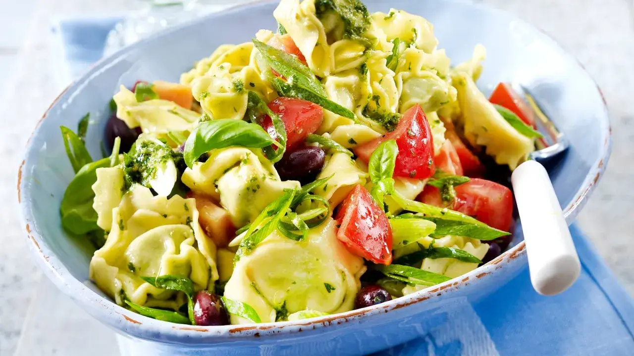 Ein bunter Tortellinisalat mit frischen Tomaten, Oliven, Basilikum und einem leckeren Pesto.