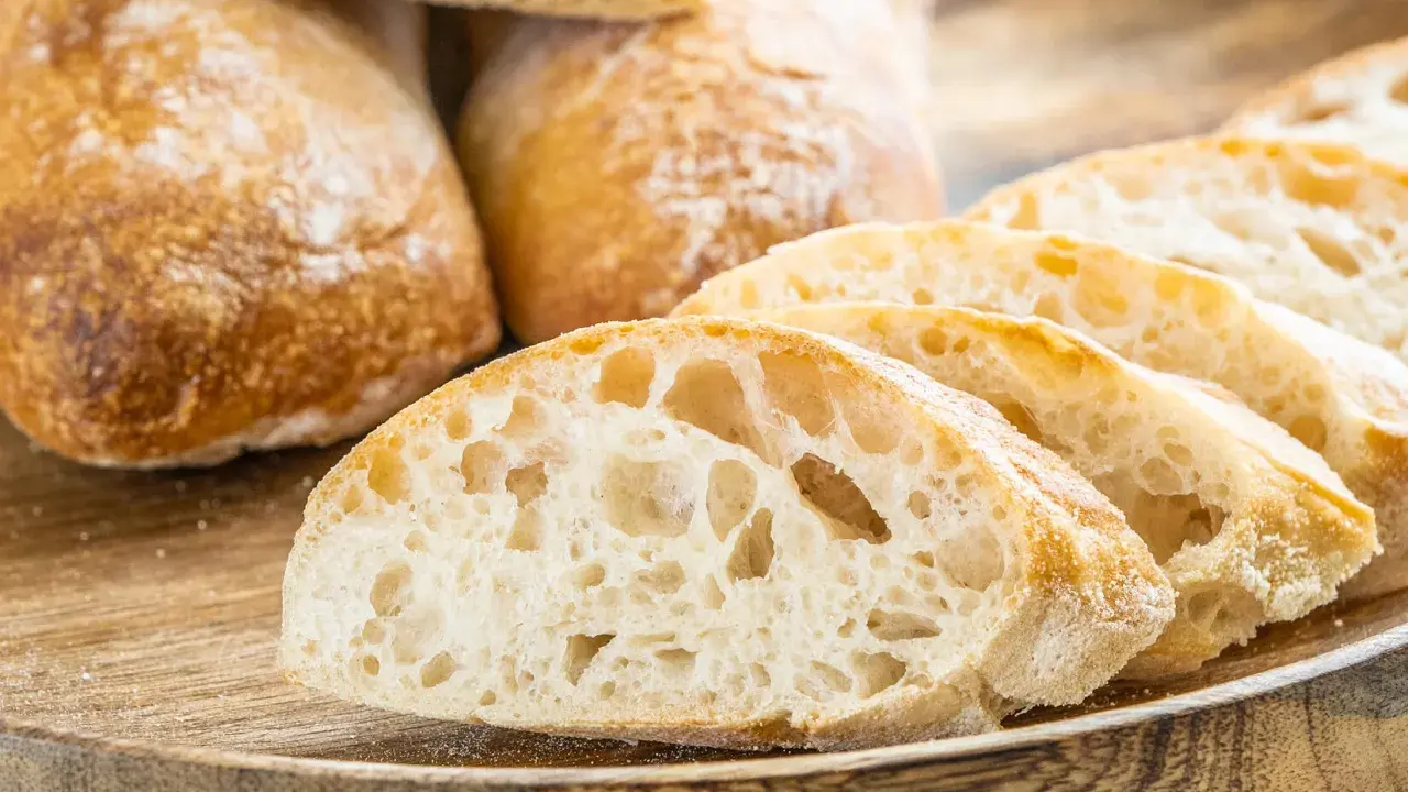 Frisch gebackene Ciabatta-Brote, aufgeschnitten auf einem Holzbrett. Dieses Ciabatta Rezept ergibt luftiges Brot mit knuspriger Kruste.