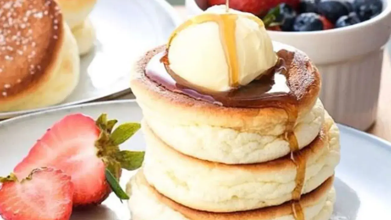 Fluffige japanische Pancakes mit einer Kugel Eis, Sirup und frischen Beeren.