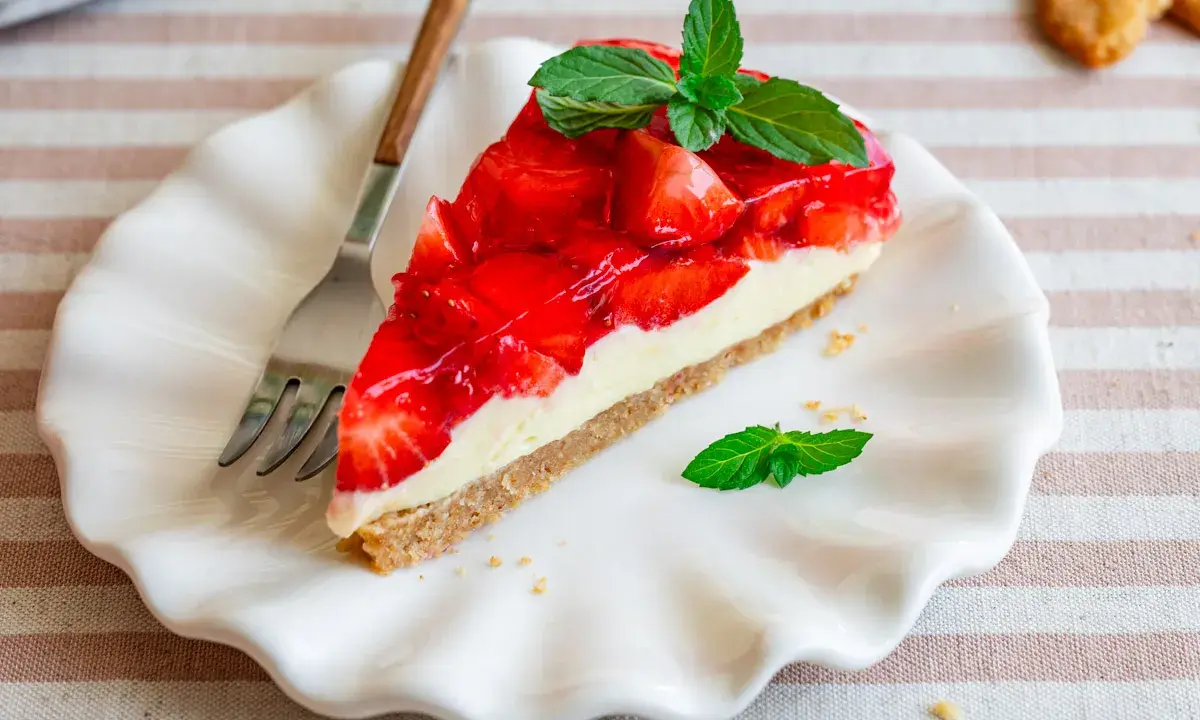 Ein Stück Erdbeerkuchen mit einer cremigen Füllung und glänzender Erdbeerschicht, garniert mit Minze. Diese torte ohne sahne ist ein Genuss.
