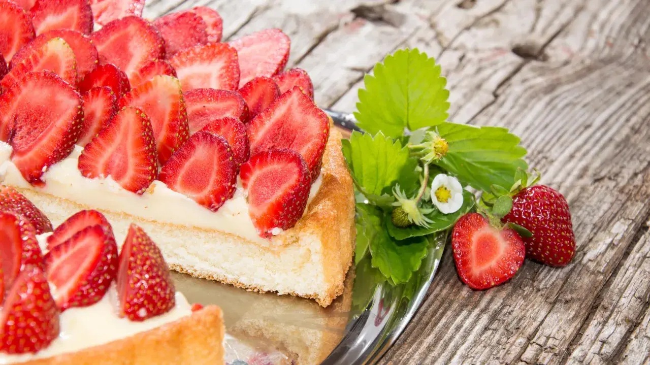 Ein köstlicher Erdbeerkuchen mit frischen Erdbeeren und Sahne auf einem Silbertablett. Perfekt für ein Erdbeerkuchen Rezept.