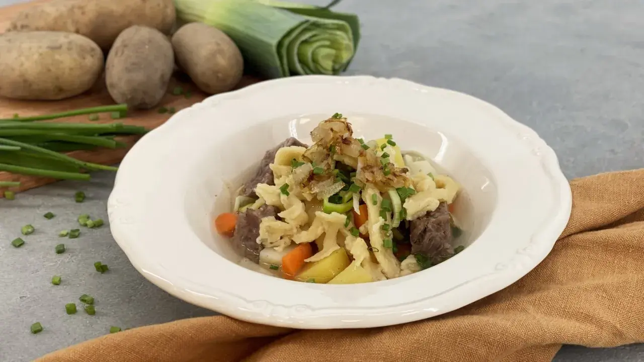 Herzhafter Gaisburger Marsch mit zarten Spätzle, Rindfleisch, Kartoffeln und Karotten, garniert mit Röstzwiebeln und Schnittlauch.
