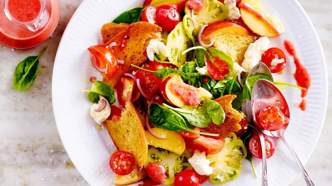 Bunter Salat mit Tomaten, Pfirsich, Brot und Käse – ein Fest für die Sinne und ein Beispiel für raffinierte Sommersalate.