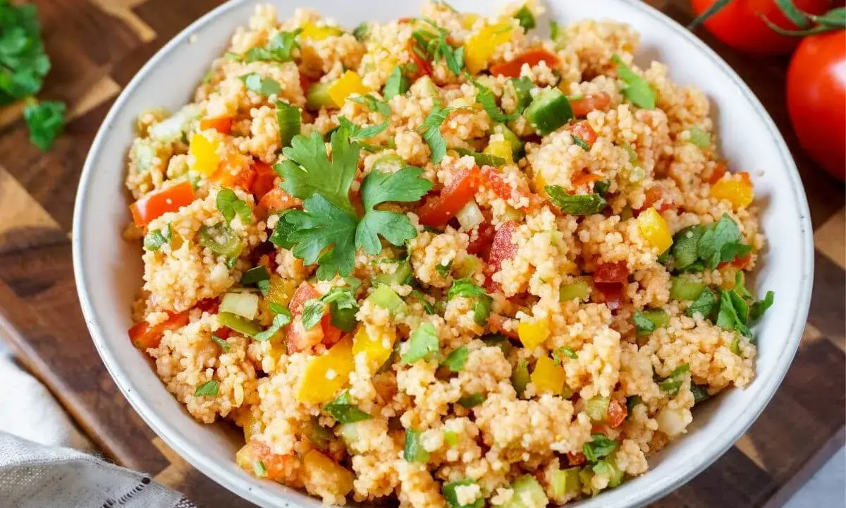 Frischer Couscous-Salat mit Tomaten, Paprika und Petersilie, garniert mit einem Petersilienblatt.