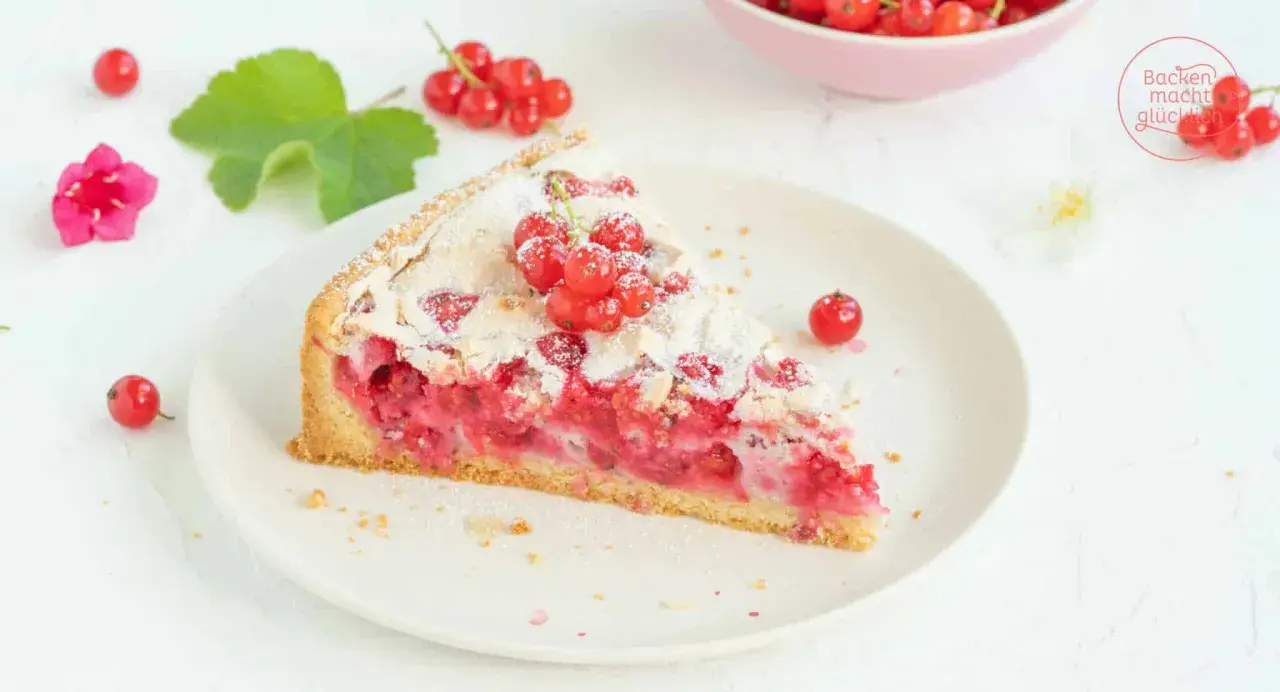Ein Stück von Omas Johannisbeerkuchen mit Baiser, garniert mit frischen roten Johannisbeeren und Puderzucker.