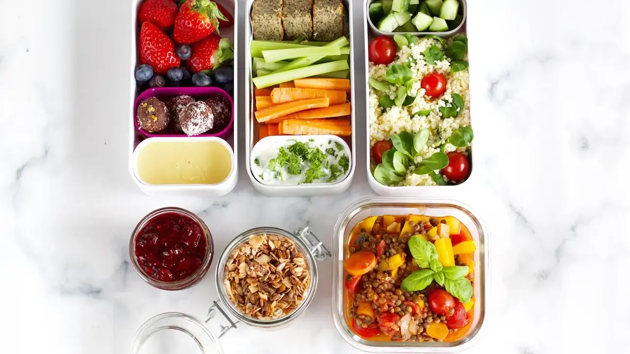 Vorbereitete Mahlzeiten für das meal prep einfrieren: Obst, Gemüse-Sticks, Hummus, Couscous-Salat und Linseneintopf.