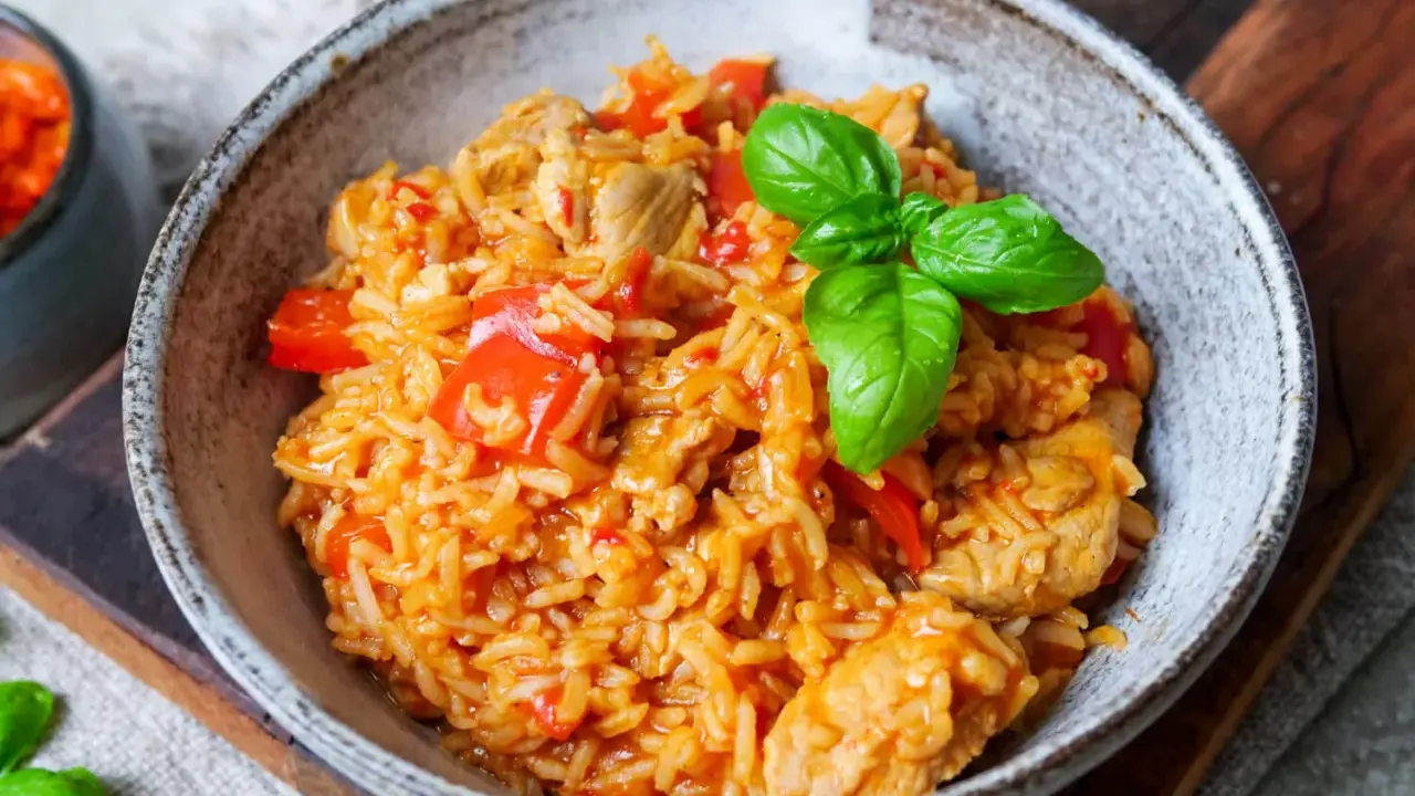 Herzhaftes serbisches Reisfleisch mit Paprika und Basilikum in einer rustikalen Schüssel, bereit zum Genießen.