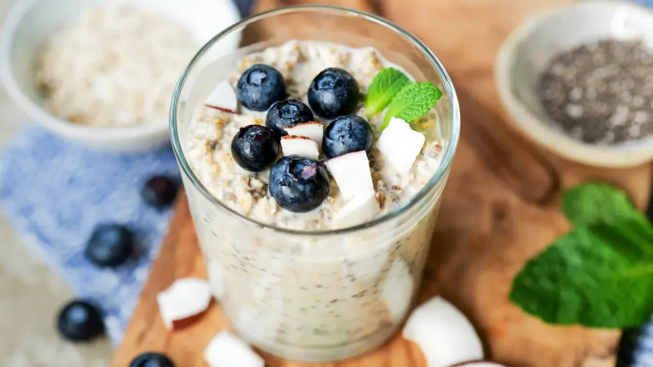 Ein Glas cremiger Overnight Oats mit Blaubeeren, Kokosnuss und Minze. Perfekt für ein schnelles Frühstück.