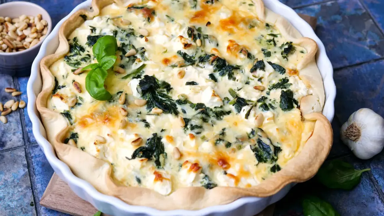Herzhafte Quiche mit Spinat und Feta, garniert mit Pinienkernen und Basilikum.