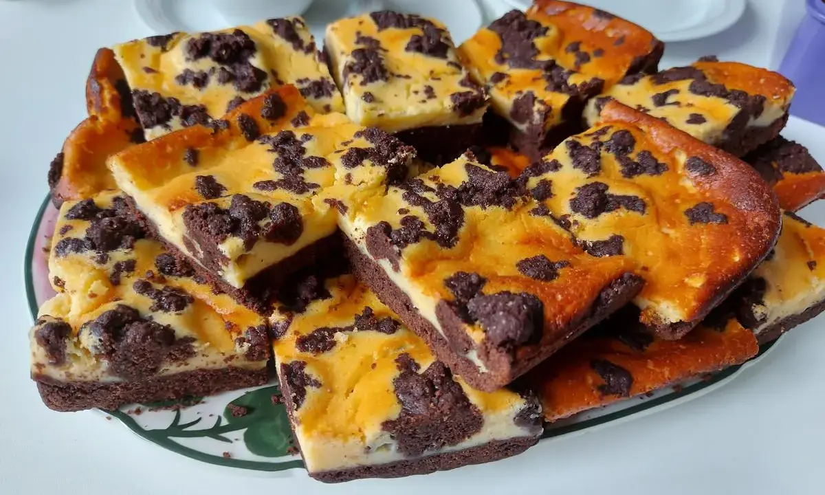 Ein Blech russischer Zupfkuchen, in Stücke geschnitten, mit Schokoladenstreuseln und cremiger Füllung.
