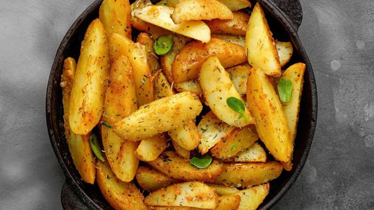 Goldbraune Ofenkartoffeln, gewürzt mit Kräutern, in einer schwarzen Pfanne. Perfekt für ein einfaches Ofenkartoffeln Rezept.