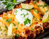 Herzhafte Enchiladas mit geschmolzenem Käse, saurer Sahne und Limettenspalten. Ein köstliches Enchiladas Rezept, das man probieren muss!
