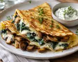 Herzhafte Pfannkuchen gefüllt mit Pilzen und Spinat, überbacken mit Käse, serviert mit Kräuterquark.