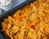 Herzhaftes One Pot Reis Ofen Gericht mit Hähnchenstreifen und bunten Paprikastreifen, serviert in einer schwarzen Auflaufform.