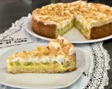 Ein köstlicher Rhabarberkuchen mit Pudding und Baiser, bestreut mit Mandelblättchen. Ein Stück Glück auf einem Teller.
