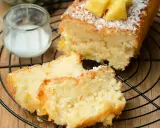 Saftiger ananas kokos kuchen mit frischer Ananas und Kokosraspeln, serviert auf einem Gitter mit einem Glas Milch.