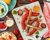 Würstchen, Maiskolben, Nudelsalat und Kräuterbutter – alles für ein perfektes Grill-Beilagen-Festmahl.