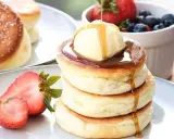 Fluffige japanische Pancakes mit einer Kugel Eis, Sirup und frischen Beeren.