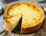 Ein saftiger Mandarinen Schmand Kuchen mit einem knusprigen Boden und cremiger Füllung, ein Stück wurde bereits herausgeschnitten.