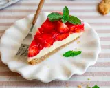 Ein Stück Erdbeerkuchen mit einer cremigen Füllung und glänzender Erdbeerschicht, garniert mit Minze. Diese torte ohne sahne ist ein Genuss.
