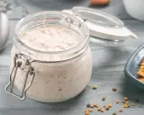 Ein Glas cremiger Haferflocken-Pudding steht bereit, daneben eine Schale mit Pollen und ein Löffel.