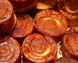 Nahaufnahme von karamellisierten Kouign Amann Gebäckstücken mit spiralförmiger Teigstruktur.