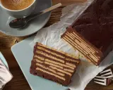 Ein Stück Schokoladenkuchen, der wie ein kalter Hund aussieht, mit Keksen und Schokoladencreme geschichtet. Daneben eine Tasse Kaffee.