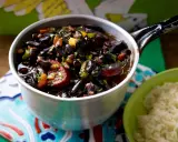 Herzhaftes schwarze bohnen rezept im Topf, mit Wurst und Gemüse, daneben eine Schüssel Reis.