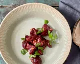 Ein köstlicher Rote Bete Feta Salat mit frischer Petersilie, serviert auf einem rustikalen Teller. Daneben liegen Löffel und Gabel.