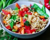 Bunter mie nudelsalat mit Erdnüssen, Paprika, Zuckerschoten und Karotten, garniert mit Petersilie.