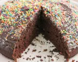 Schokoladenkuchen ohne Mehl und Ei, mit glänzender Glasur und bunten Streuseln. Ein Stück fehlt, was Lust auf mehr macht.