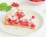 Ein Stück von Omas Johannisbeerkuchen mit Baiser, garniert mit frischen roten Johannisbeeren und Puderzucker.