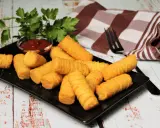 Goldbraune Kroketten, frisch zubereitet, liegen auf einem schwarzen Teller. Dazu gibt es Ketchup und frische Petersilie. Perfekt zum selber machen!
