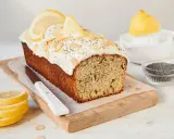 Saftiger zitronen mohn kuchen mit weißem Zuckerguss, Mandelsplittern und Mohn bestreut. Zitronenscheiben zieren die Oberseite.