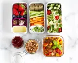 Vorbereitete Mahlzeiten für das meal prep einfrieren: Obst, Gemüse-Sticks, Hummus, Couscous-Salat und Linseneintopf.
