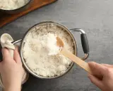 Hände halten einen Topf mit frisch gekochtem Reis. Eine Holzschaufel hebt eine Portion Reis heraus. Die Frage "wie lange kocht man reis" wird hier visuell beantwortet.