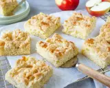 Saftiger Apfelkuchen vom Blech mit knuspriger Streuselhaube. Ein Stück wird gerade mit einem Kuchenheber herausgenommen.