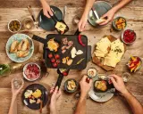 Raclette-Abend: Käse schmilzt, Fleisch brät, dazu Brot, Oliven, Paprika und Pilze – so vielfältig, was man zu Raclette essen kann!
