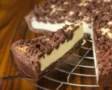 Ein Stück russischer Zupfkuchen wird aus dem Ganzen gehoben. Der Kuchen hat einen dunklen Boden, eine helle Füllung und eine krümelige Schokoladenstreusel-Decke.