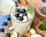 Ein Glas cremiger Overnight Oats mit Blaubeeren, Kokosnuss und Minze. Perfekt für ein schnelles Frühstück.