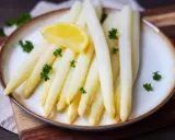 Frischer weißer Spargel, perfekt gekocht, garniert mit Petersilie und einer Zitronenspalte auf einem Teller. Ein Genuss, wenn Spargel Saison hat.