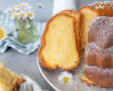 Saftiger Omas Joghurt Kuchen, mit Puderzucker bestäubt und Zitronenschale garniert. Ein Stück davon liegt auf einer Gabel.