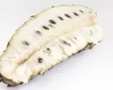 Aufgeschnittene Soursop-Frucht mit weißem Fruchtfleisch und dunklen Kernen, bereit für den Genuss.