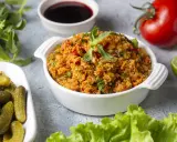 Ein köstliches Kisir-Rezept mit Bulgur, Tomaten und Kräutern, garniert mit Minze. Daneben Cornichons, Granatapfelsirup, Limette und ein frischer Kopfsalat.