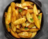 Goldbraune Ofenkartoffeln, gewürzt mit Kräutern, in einer schwarzen Pfanne. Perfekt für ein einfaches Ofenkartoffeln Rezept.